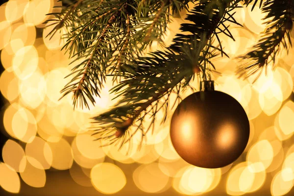 Close up view of golden christmas ball hanging on pine tree with bokeh lights background — Stock Photo