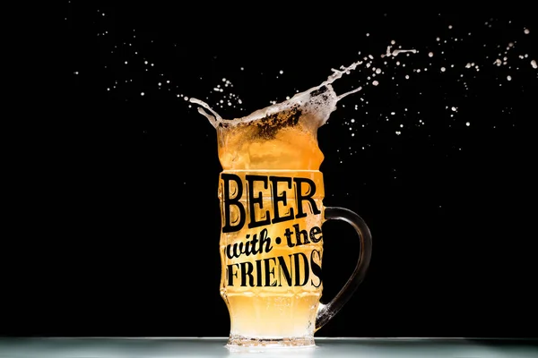 Mug of light  beer with foam and splashes at table on black background with 