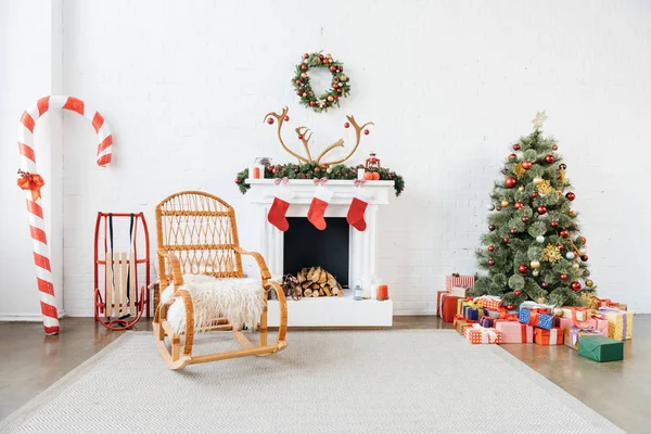 Quarto decorado com cadeira de balanço, árvore de natal e presentes para feriados de inverno celebração — Fotografia de Stock