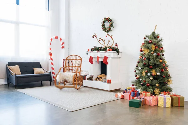 Habitación decorada con mecedora, árbol de Navidad y regalos para la celebración de las vacaciones de invierno - foto de stock