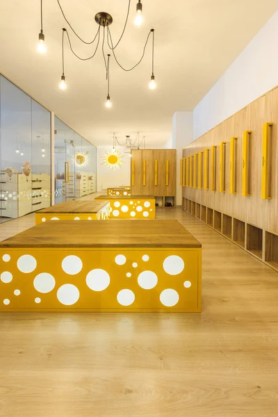 Wooden lockers, benches and mirror in illuminated kindergarten cloakroom — Stock Photo