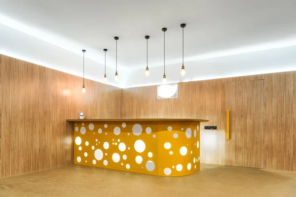 Illuminated lamps and yellow reception desk in modern kindergarten — Stock Photo