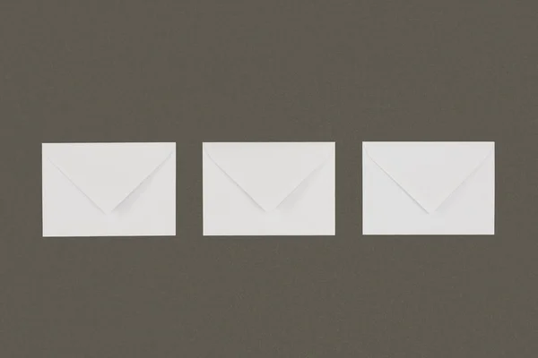 Top view of three closed white envelopes arranged isolated on grey background — Stock Photo