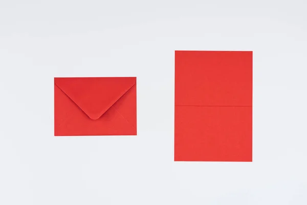 Vista de primer plano del sobre rojo cerrado y la tarjeta aislada en blanco - foto de stock