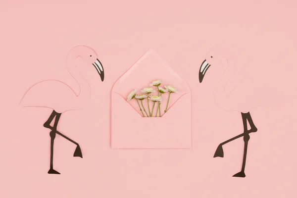 Vista close-up de envelope rosa aberto com pequenas flores brancas e flamingos corte de papel isolado em rosa — Fotografia de Stock