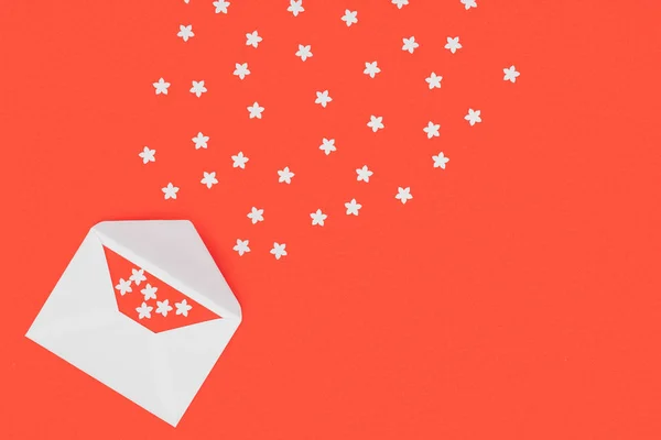 Top view of open white envelope with red card and small white stars isolated on red background — Stock Photo