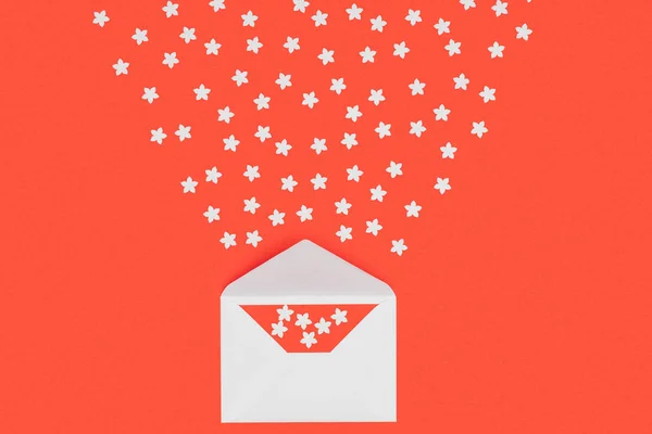 Close-up view of white envelope with red card and small white stars isolated on red — Stock Photo