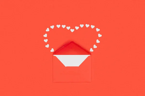 Vue du dessus de l'enveloppe rouge avec carte blanche et petits coeurs isolés sur rouge — Photo de stock
