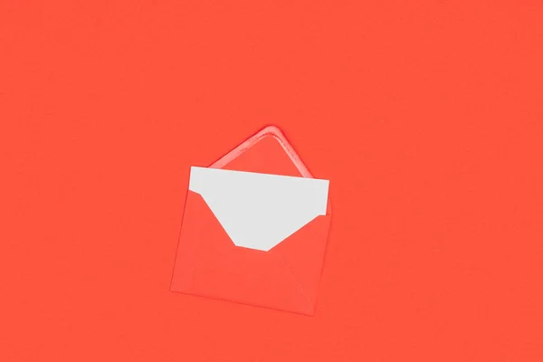 Draufsicht auf geöffneten roten Umschlag mit leerer weißer Karte isoliert auf rot — Stockfoto