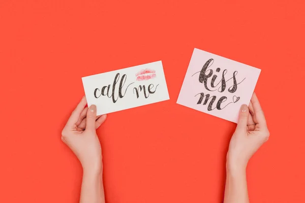 Partial top view of person holding cards with kiss me and call me inscriptions and kiss mark isolated on red — Stock Photo