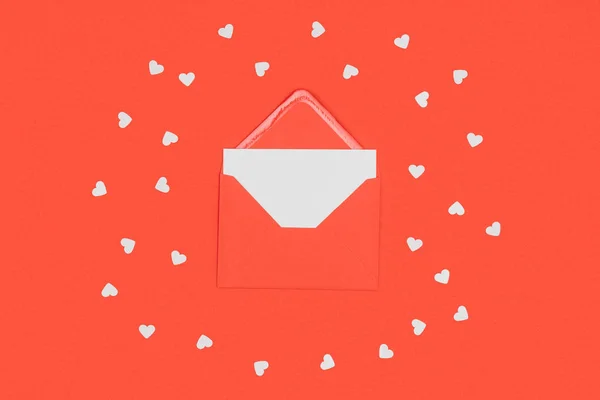 Nahaufnahme von rotem Umschlag mit weißer Karte und kleinen Herzen auf rotem Papier — Stockfoto