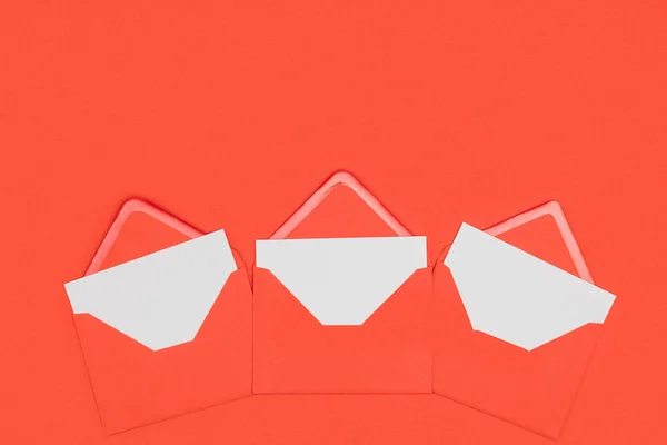 Sobres rojos abiertos con tarjetas blancas aisladas en rojo - foto de stock