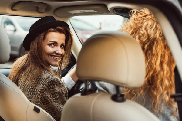 Portrait of smiling woman driving car while her female friend sitting near — Stock Photo