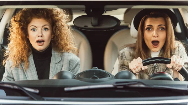 Portrait of shocked beautiful adult female friends sitting in car — Stock Photo