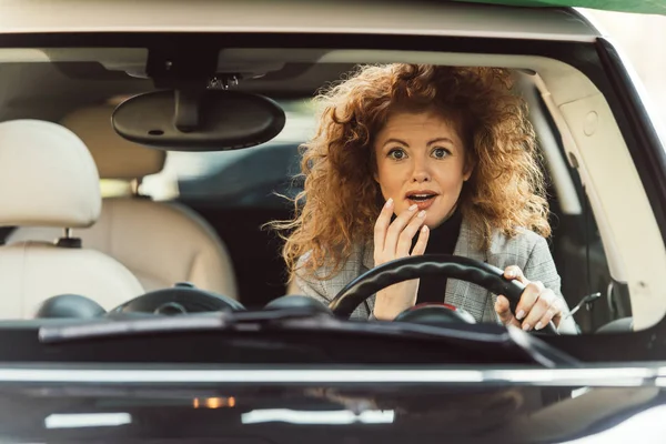Surpresa adulto gengibre encaracolado mulher sentado no volante no carro — Fotografia de Stock