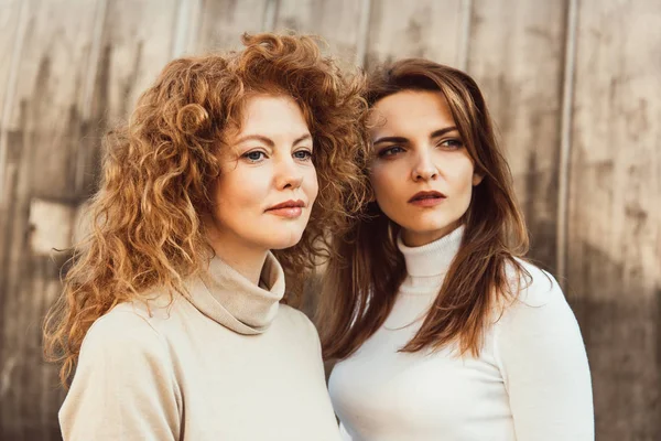 Portrait of pretty female friends in turtle necks looking away at urban street — Stock Photo