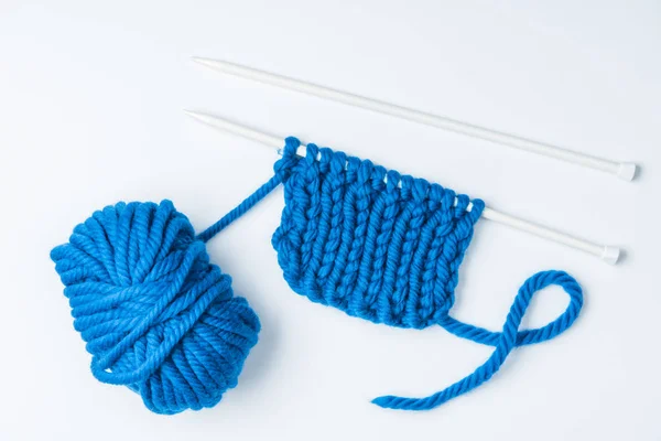 Top view of blue yarn and knitting needles on white backdrop — Stock Photo