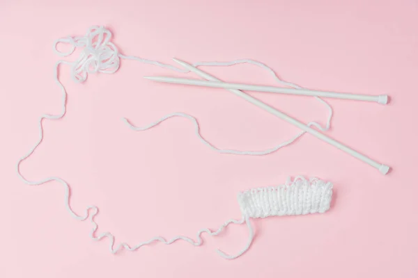 Flat lay with white yarn and knitting neeldes on pink backdrop — Stock Photo