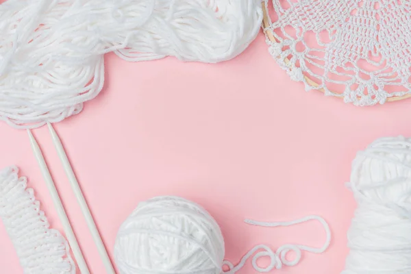 Vue de dessus des fils blancs et des aiguilles à tricoter sur fond rose — Photo de stock