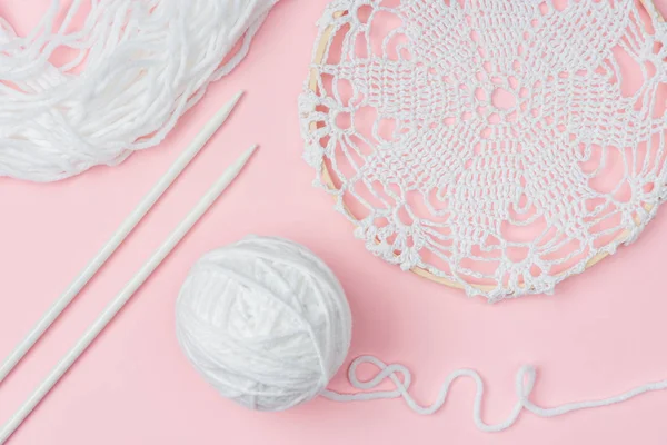 Flat lay with white yarn and knitting needles on pink backdrop — Stock Photo