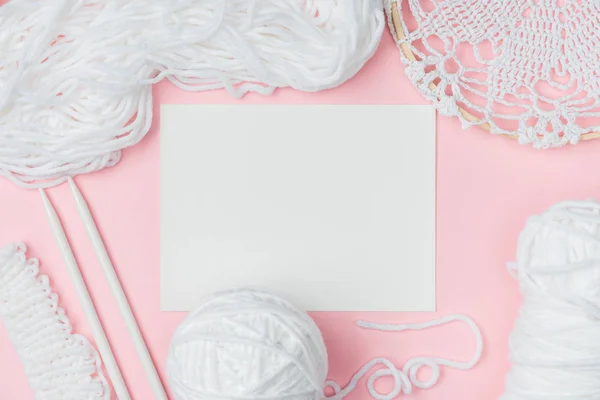 Deitado plano com fios brancos, agulhas de tricô e papel em branco sobre fundo rosa — Fotografia de Stock