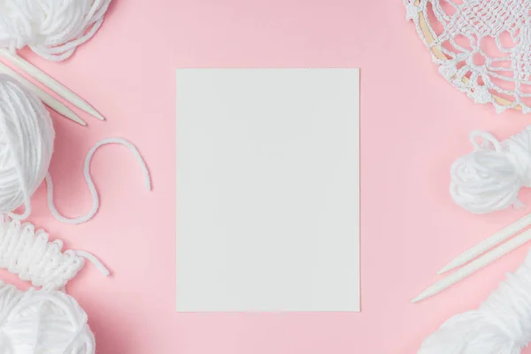 Plat avec fil blanc, aiguilles à tricoter et papier blanc sur fond rose — Photo de stock