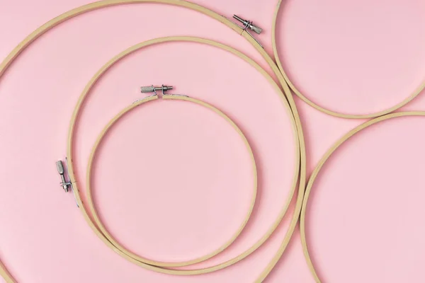 Flat lay with wooden embroidery hoops arranged on pink background — Stock Photo