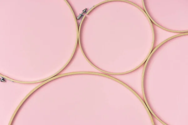 Posa piatta con cerchi da ricamo in legno disposti su sfondo rosa — Foto stock
