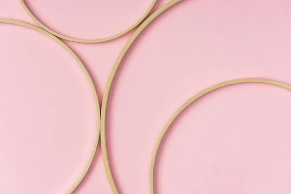 Flat lay with wooden embroidery hoops arranged on pink background — Stock Photo