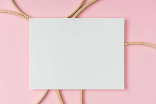 Flat lay com aros de bordado de madeira e papel em branco dispostos sobre fundo rosa — Fotografia de Stock