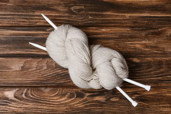 Vue du dessus du fil blanc griffe avec aiguilles à tricoter sur le dessus de la table en bois — Photo de stock