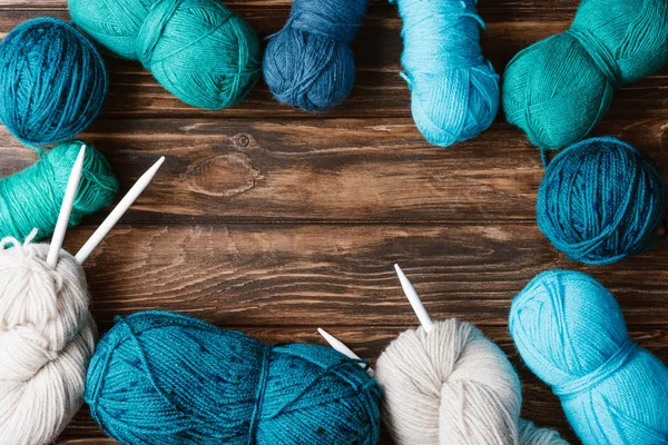 Flat lay with arranged yarn clews and knitting needles on wooden surface — Stock Photo