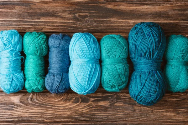 Top view of green and blue knitting yarn clews on wooden surface — Stock Photo