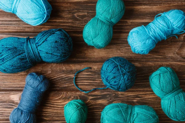 Top view of green and blue knitting yarn clews on wooden surface — Stock Photo