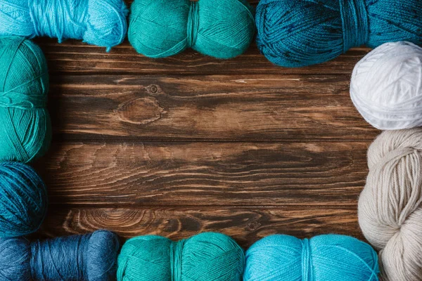 Flat lay with arranged blue, white and green yarn clews on wooden tabletop — Stock Photo