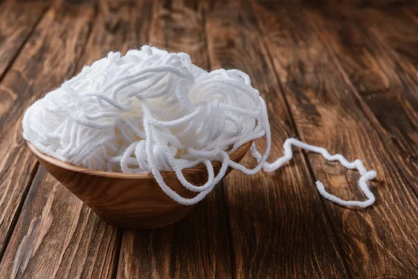 Close up view of white yarn in bowl on wooden tabletop — Stock Photo