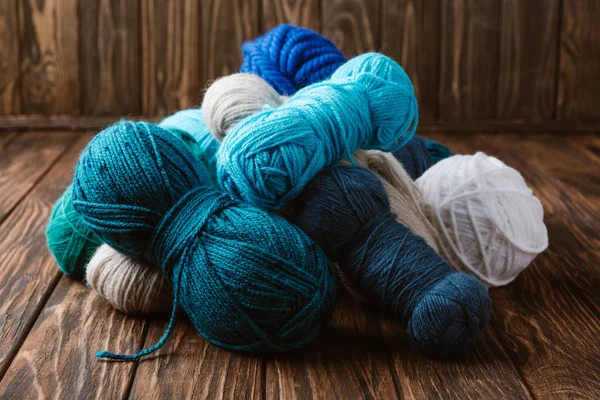 Close up view of white, blue and green yarn for knitting on wooden surface — Stock Photo