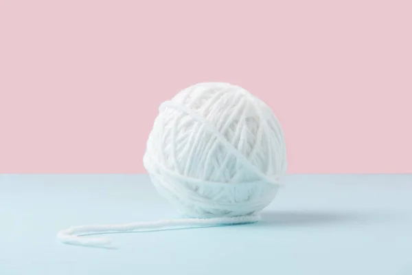 Vue rapprochée de boule de fil blanc sur fond bleu et rose — Photo de stock