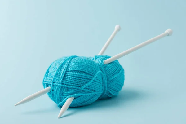 Close up view of blue yarn clew and knitting needles on blue background — Stock Photo