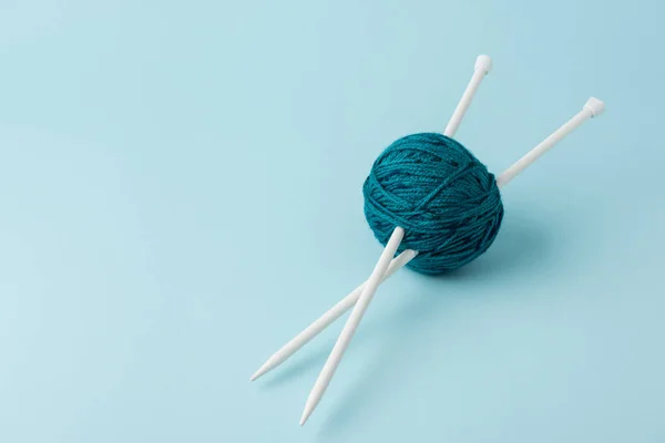 Vue rapprochée de la boule de fil et des aiguilles à tricoter sur fond bleu — Photo de stock