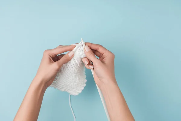 Visão parcial da mulher com fios brancos e agulhas de tricô tricô no fundo azul — Fotografia de Stock