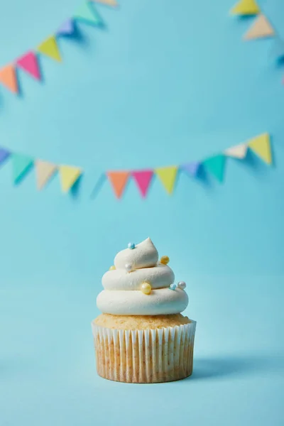Delicioso cupcake com açúcar polvilha no fundo azul com bunting — Fotografia de Stock