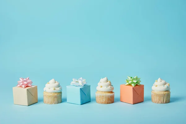 Deliciosos cupcakes y regalos difrentes sobre fondo azul - foto de stock