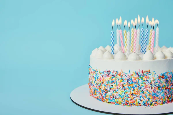 Köstliche Geburtstagstorte mit brennenden Kerzen auf blauem Hintergrund — Stockfoto