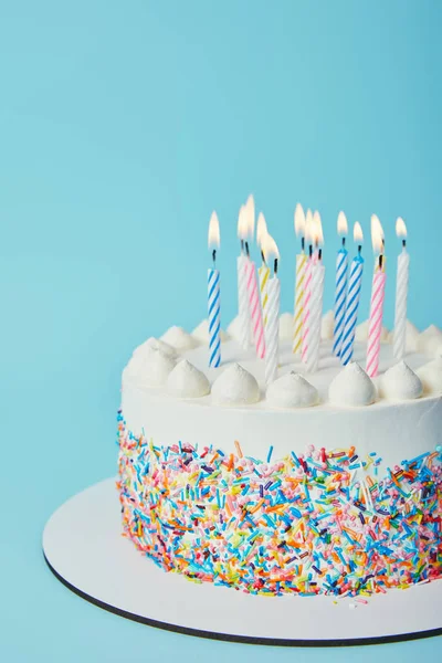 Bolo de aniversário com velas de iluminação no fundo azul — Fotografia de Stock