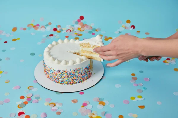 Vista parziale della donna che prende pezzo di deliziosa torta su sfondo blu — Foto stock