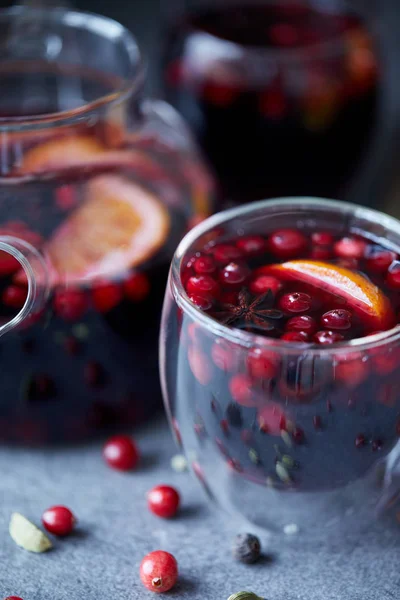 Close-up de saboroso vinho caseiro mulled com cranberries e laranja na mesa na cozinha — Fotografia de Stock