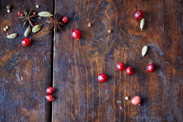 Verstreute Preiselbeeren, Nelken und Pfeffer auf Holztisch in der Küche — Stockfoto