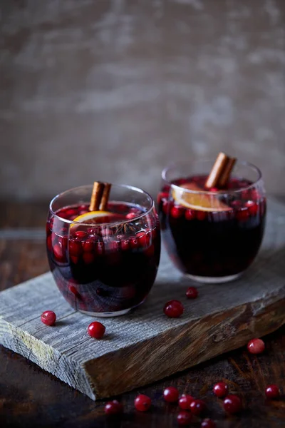 Dois copos de vinho caseiro mulled com cranberries e paus de canela em suporte de madeira na cozinha — Fotografia de Stock