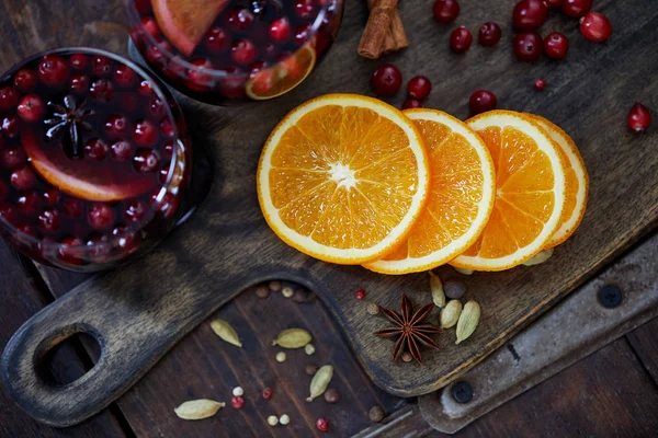 Vista superior de vinho ruminado caseiro com cranberries e laranjas na placa de corte na cozinha — Fotografia de Stock